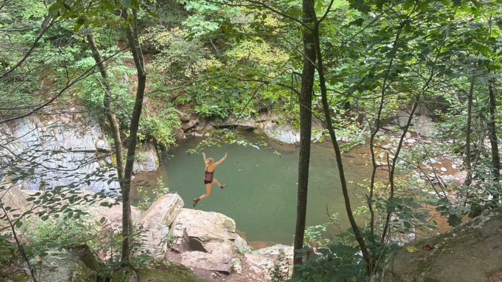 Woman jumping into a spring fed swimming hole in the mountains