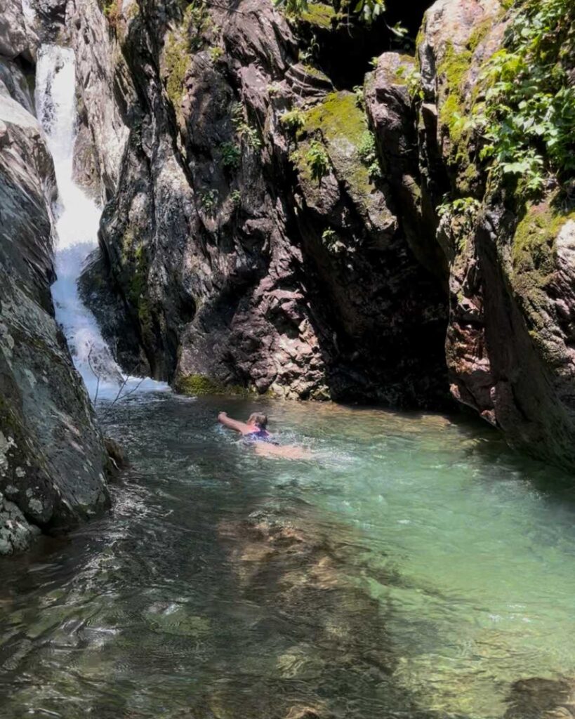 Woman swimming near a waterfall in a rocky gorge