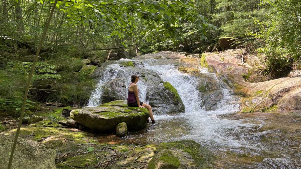 woman sitting on a rock looking at a waterfall